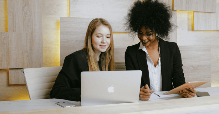 White woman and black woman recruiters reviewing candidate skills on laptop