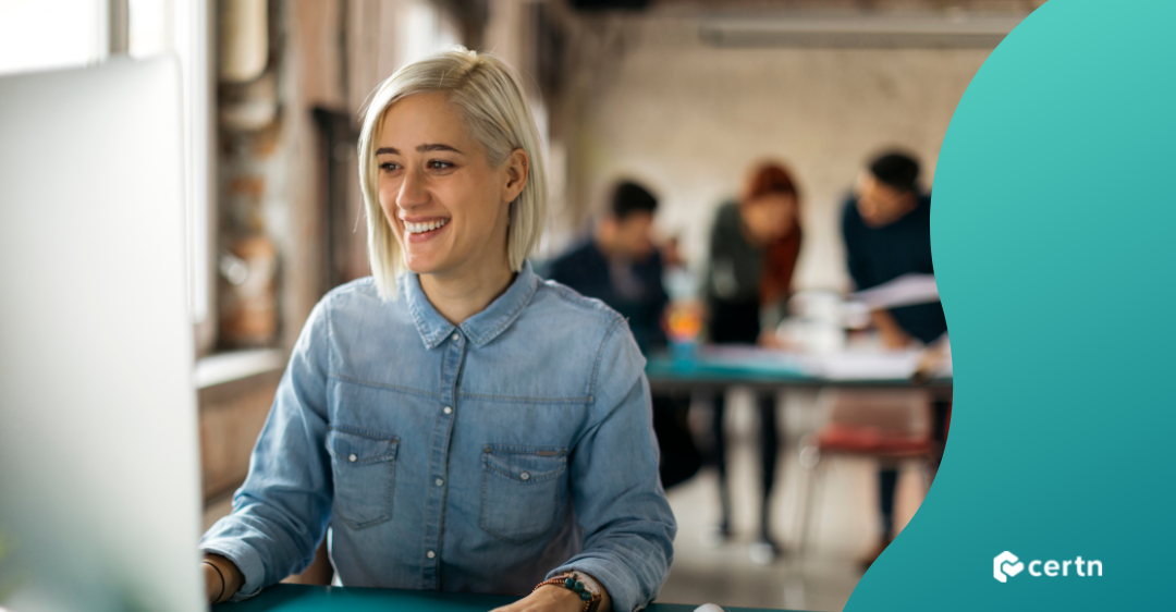 blonde female employee working at computer smiling from good work culture
